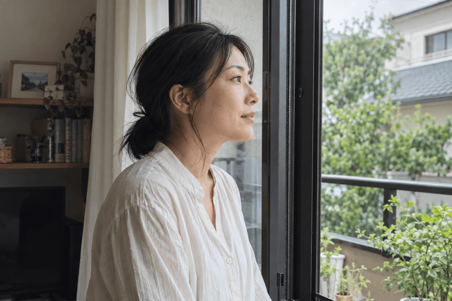 窓辺で外の緑を眺める女性のイメージ